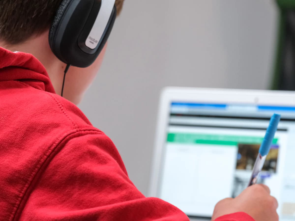 A student attending an online class with headphones and a laptop